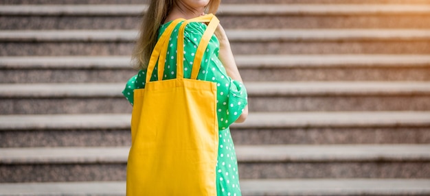 Jeune femme belle avec un sac écologique en lin jaune sur fond de ville