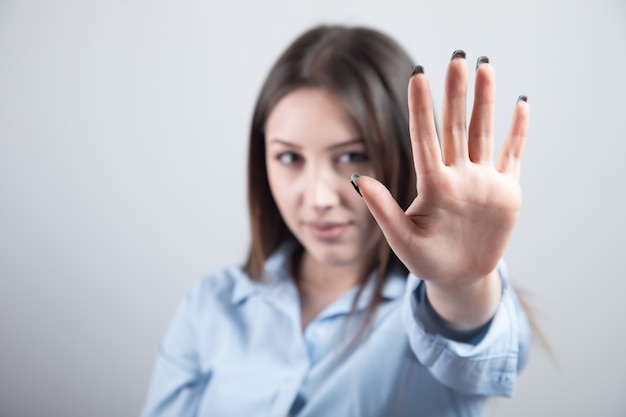 Photo jeune femme belle sérieuse montrant un panneau d'arrêt