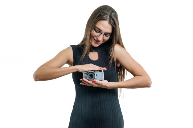 Jeune femme belle souriante à lunettes robe noire tenant l&#39;appareil photo dans ses mains