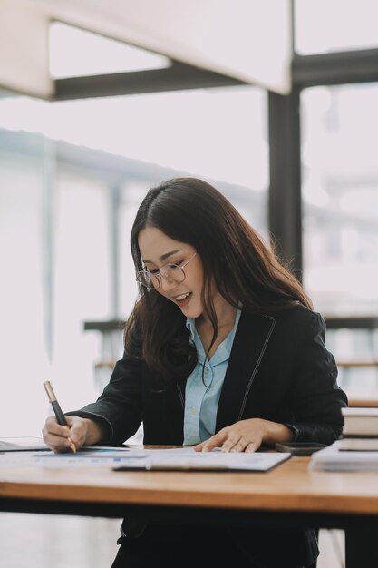 Une jeune femme belle tapant sur une tablette et un ordinateur portable alors qu'elle est assise à la table en bois du bureau moderne