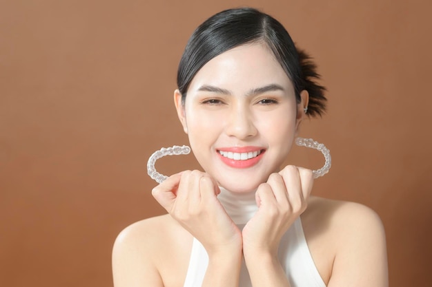 Une jeune femme avec de belles dents tient le concept dentaire sain Invisalign