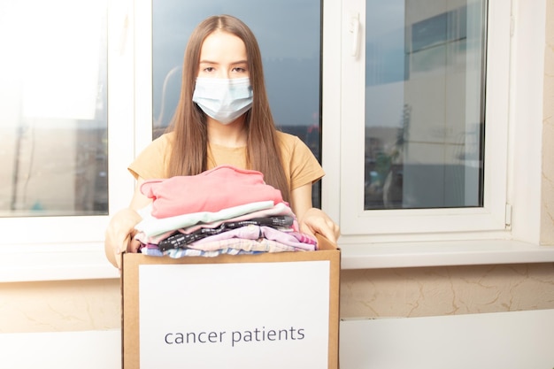 Une jeune femme bénévole avec une boîte de vêtements pour les patients atteints de cancer au centre d'aide