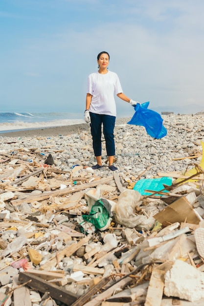 Jeune femme bénévole sur la plage pleine d'ordures