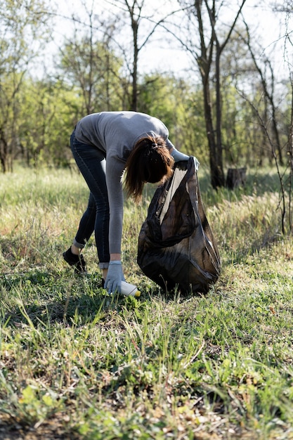 Jeune femme bénévole ramasse les ordures dans le parc. concept de protection de l'environnement contre les ordures. Pollution planétaire