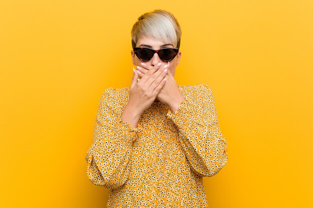 Jeune femme bien roulée portant un vêtement d'été floral choqué couvrant la bouche avec les mains.