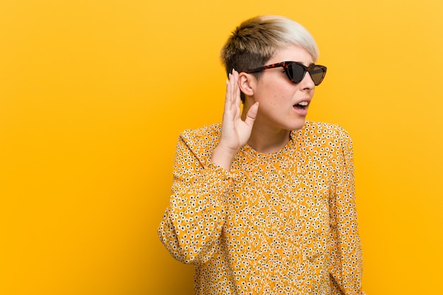 Jeune femme bien roulée portant un vêtement d'été floral essayant d'écouter un potin.