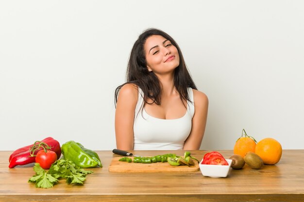 Jeune femme bien roulée prépare un repas sain en rêvant d'atteindre les objectifs et les buts