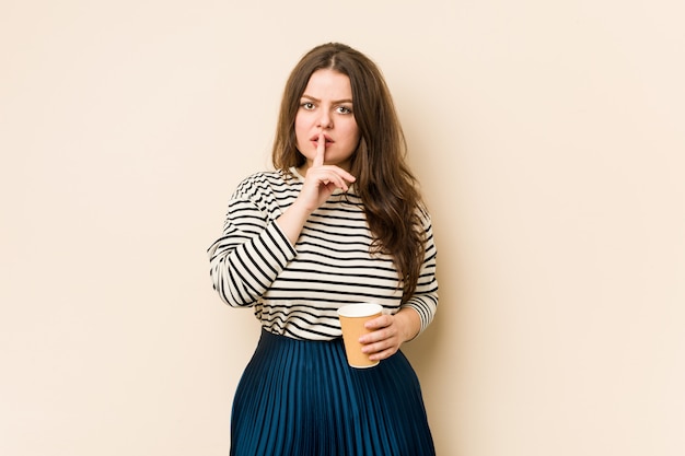 Jeune femme bien roulée tenant un café en gardant un secret ou en demandant le silence.