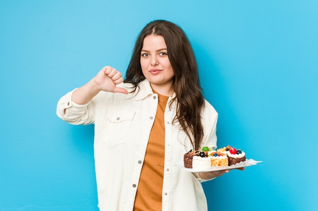 Jeune femme bien roulée tenant un gâteaux sucrés se sent fier et confiant, exemple à suivre.