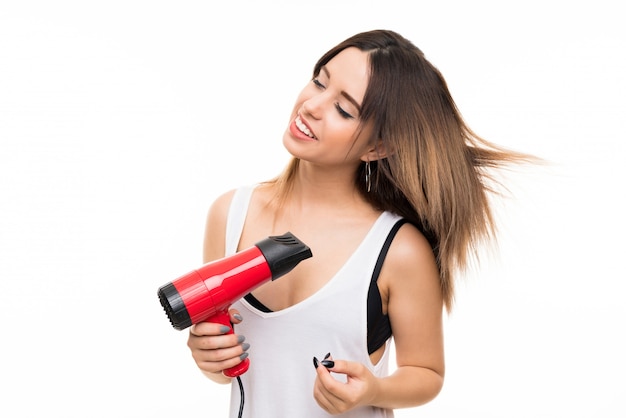 Jeune femme sur blanc isolé avec sèche-cheveux