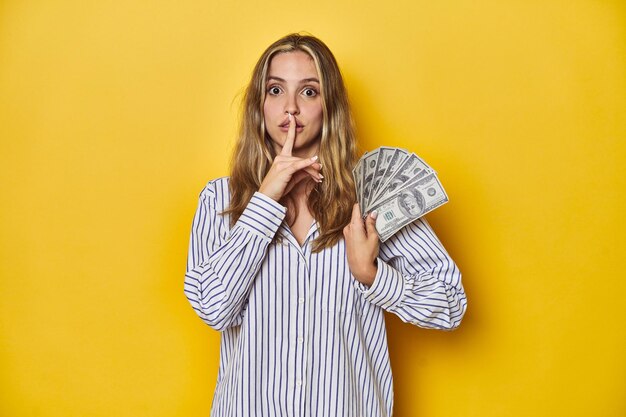 Photo jeune femme blanche tenant de l'argent gardant un secret ou demandant le silence