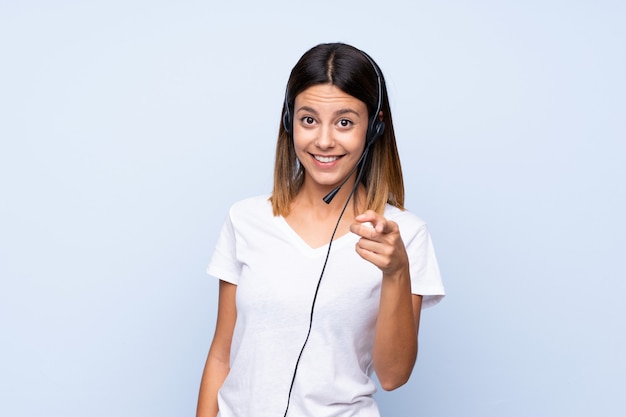 Jeune femme sur bleu isolé pointant vers l'avant