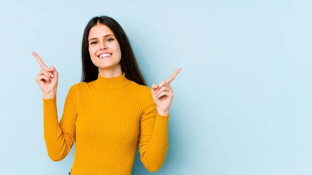 Jeune femme sur bleu pointant vers différents espaces de copie, en choisissant l'un d'eux, montrant avec le doigt.