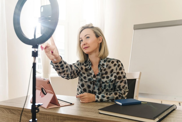 Jeune femme blogueuse ou coach lors d'une diffusion en ligne à la maison ou dans un petit bureau