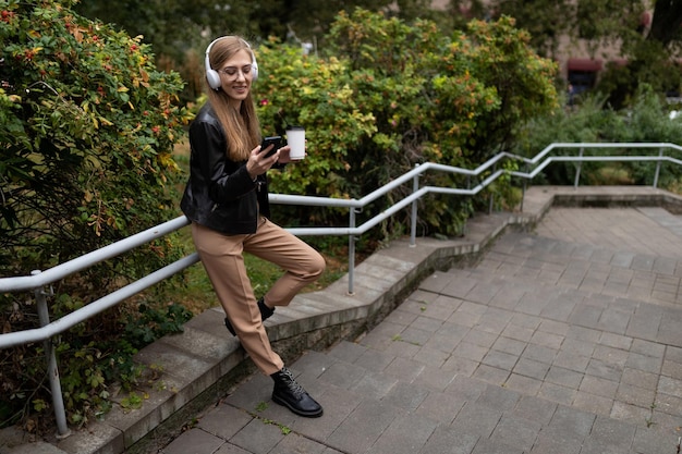 Jeune femme blogueuse écoutant de la musique avec des écouteurs dans le parc