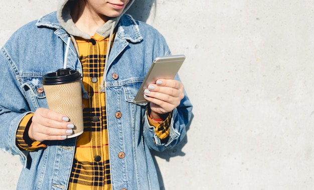 Jeune femme blogueuse parcourant les médias sociaux dans la rue. Femme SMS sur son téléphone