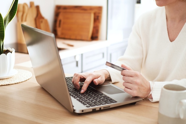 Jeune femme blonde acheter en ligne par carte de crédit sur l'ordinateur portable, faire du shopping à la maison