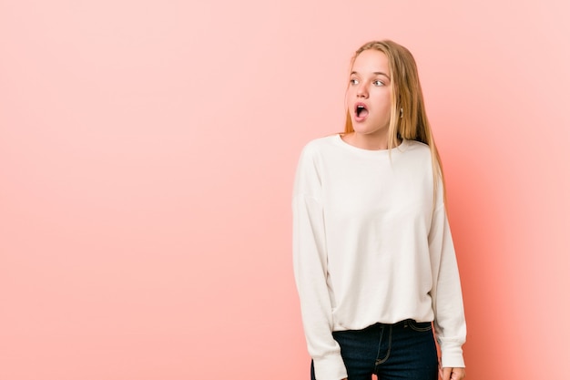 Jeune femme blonde adolescente choquée à cause de quelque chose qu'elle a vu.