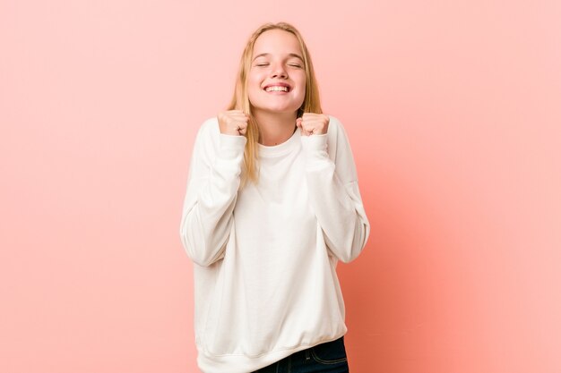 Jeune femme blonde adolescente levant le poing, se sentant heureuse et réussie. Concept de victoire.