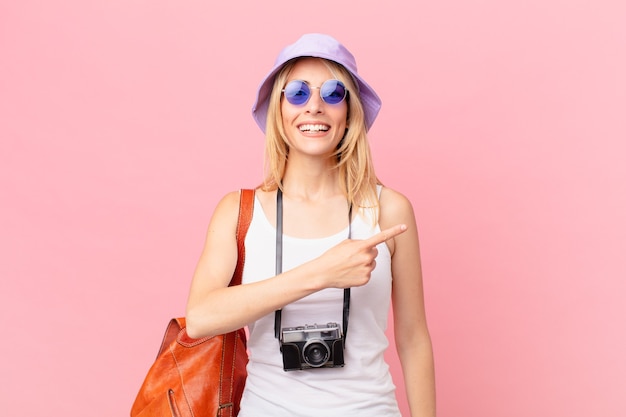 Photo jeune femme blonde à l'air excité et surpris en pointant sur le côté