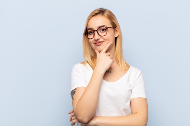 Jeune femme blonde à l'air sérieuse, réfléchie et méfiante, avec un bras croisé et la main sur le menton, options de pondération