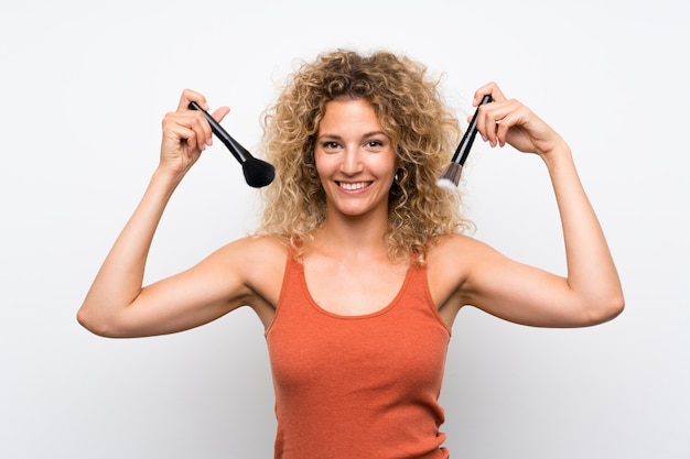 Jeune femme blonde aux cheveux bouclés avec un pinceau de maquillage