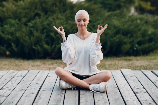 Jeune femme blonde aux cheveux courts en plein air faisant du yoga lotus