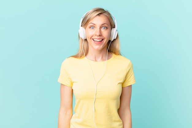 Jeune femme blonde ayant l'air heureuse et agréablement surprise et écoutant de la musique.