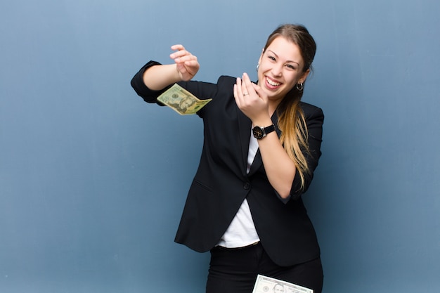 Jeune femme blonde avec des billets en dollars contre le mur de grunge