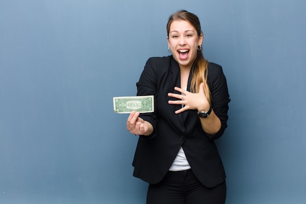 Jeune femme blonde avec des billets en dollars sur fond de mur de grunge