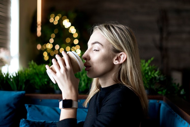 Une jeune femme blonde boit du café frais le matin au café