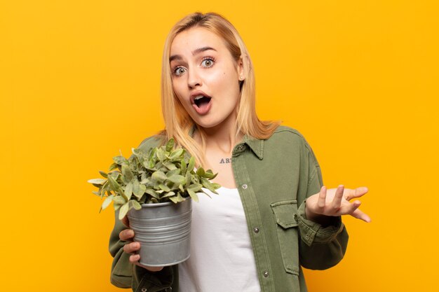 Jeune femme blonde bouche bée et étonnée, choquée et étonnée d'une incroyable surprise