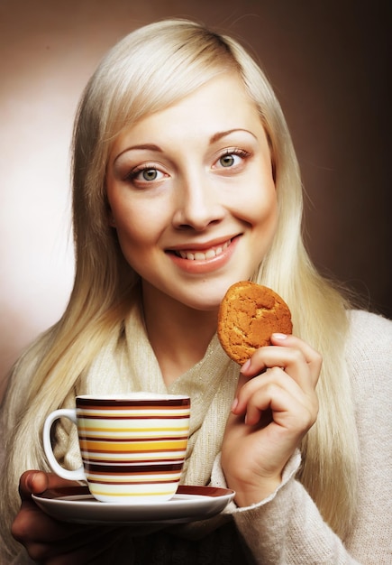 Jeune femme blonde avec café et biscuits