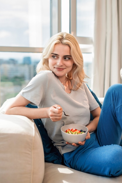 Jeune femme blonde sur un canapé avec de la bouillie saine