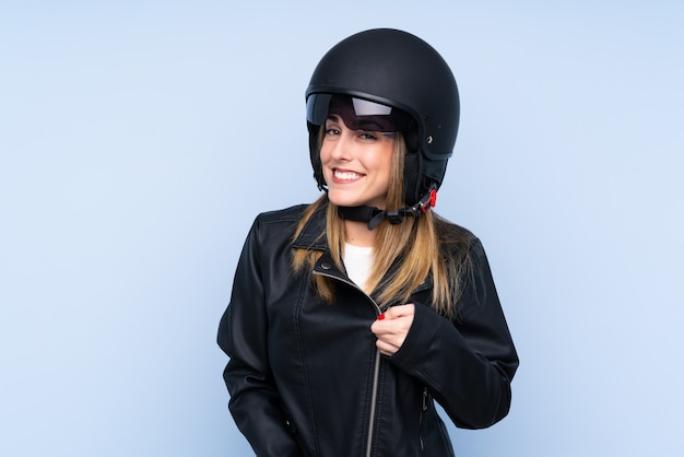 Jeune femme blonde avec un casque de moto sur mur bleu isolé