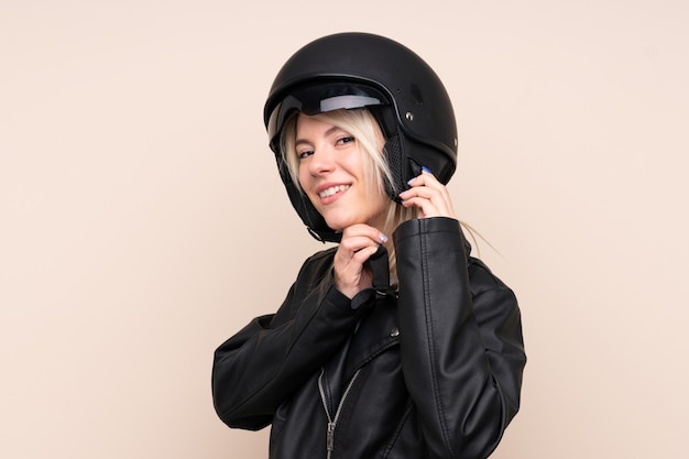 Jeune femme blonde avec un casque de moto sur mur isolé