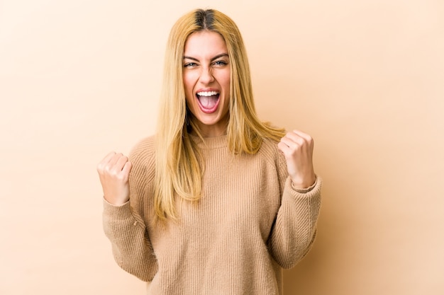 Jeune femme blonde caucasienne acclamant insouciant et excité. Concept de victoire.