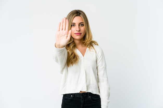 Jeune femme blonde caucasienne debout avec la main tendue montrant le panneau d'arrêt, vous empêchant.