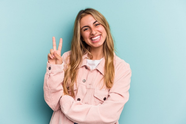 Jeune femme blonde caucasienne isolée sur fond bleu montrant le numéro deux avec les doigts.