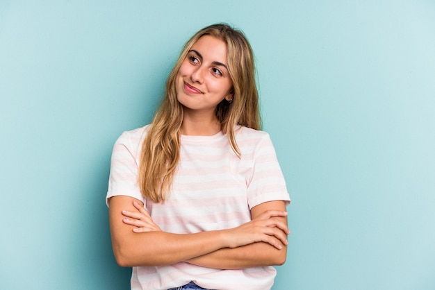 Jeune femme blonde caucasienne isolée sur fond bleu rêvant d'atteindre ses objectifs