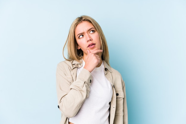 Jeune femme blonde caucasienne isolée pensant et levant, réfléchissant, contemplant, ayant un fantasme.