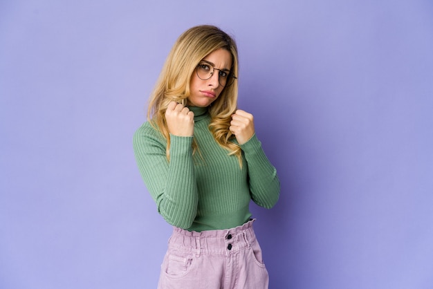 Jeune femme blonde caucasienne montrant le poing à la caméra, expression faciale agressive.