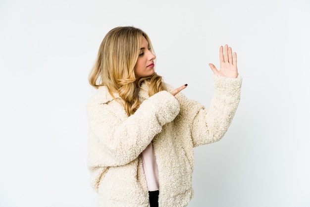 Jeune femme blonde caucasienne souriante joyeuse montrant le numéro cinq avec les doigts.