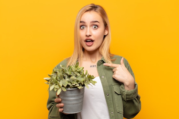 Jeune femme blonde à la choqué et surpris avec la bouche grande ouverte, pointant vers soi