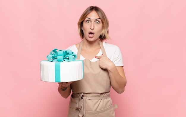 Jeune femme blonde à la choqué et surpris avec la bouche grande ouverte, pointant vers soi