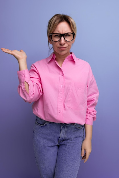 Jeune femme blonde confiante avec queue de cheval et lunettes vêtue d'une chemise rose à la mode pour le