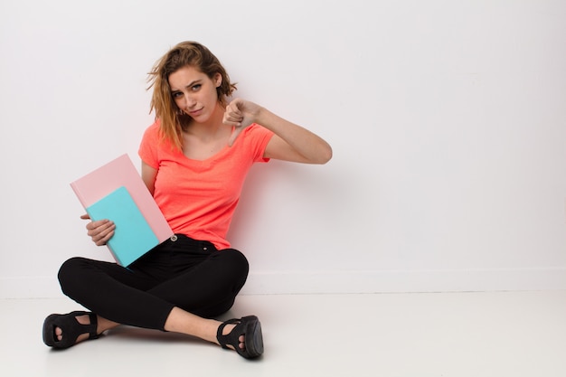 Jeune femme blonde contre le mur avec des livres