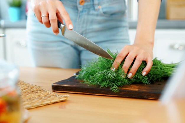 Jeune femme blonde coupe des légumes pour la salade dans sa cuisine