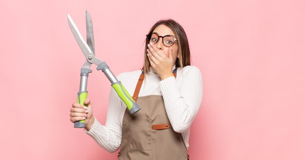 Jeune femme blonde couvrant la bouche avec les mains avec une expression choquée et surprise, gardant un secret ou disant oups