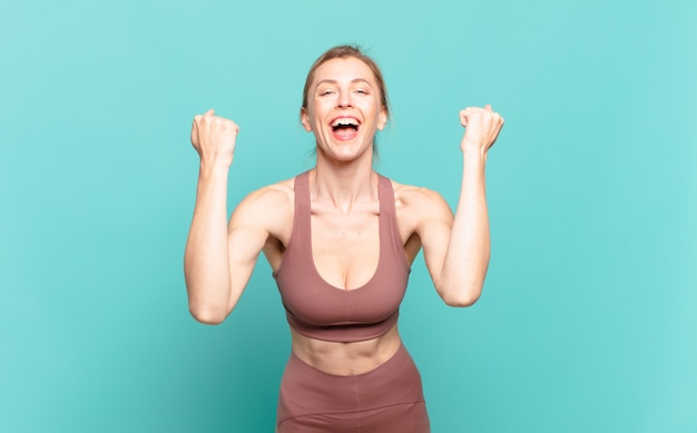 Jeune femme blonde criant agressivement avec une expression de colère ou avec les poings serrés célébrant le succès. notion de sport